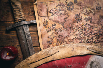 Ancient map, sword and shield on the flat lay table background.