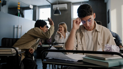 Sad worried upset disappointed caucasian student nerd wearing glasses sits in classroom at desk...