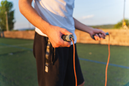 A young guy is jumping a rope outside in nature during the day