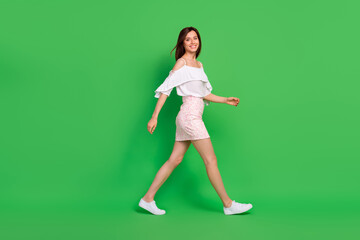Full size profile photo of positive gorgeous girl have good mood walking isolated on green color...
