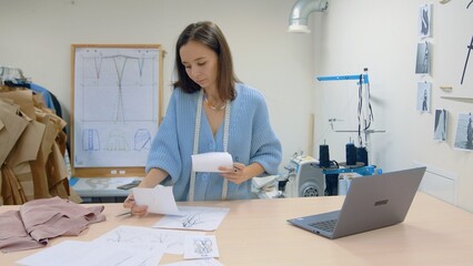 Obraz premium 4K. A young woman working in a clothing store. A fashion designer makes sketches on paper.