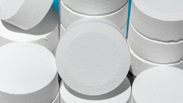Pile of white chlorine tablets for the disinfection of swimming pools at the beginning of the swimming season is a summer Maintenance of summer swimming pools with the use  chlorine tablets for water