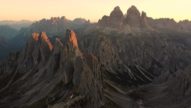 An outstanding sunrise view of Rifugio Fratelli Fonda Savio and Tre Cime di Lavaredo and the stunning mountains surrounding the guest house with beautiful colors of the sun.Location - Dolomites