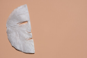 Fabric face mask on a beige background. skin care concept. Flat lay, place for text.