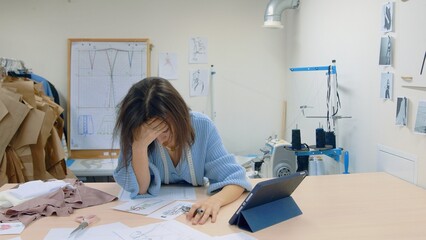 4K. A young woman working in a clothing store. A tired female fashion designer makes sketches on paper.