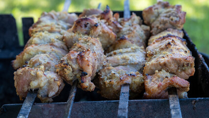 Preparing grilled pork kebab. Closeup top view of grilling fresh meat on metal skewers.