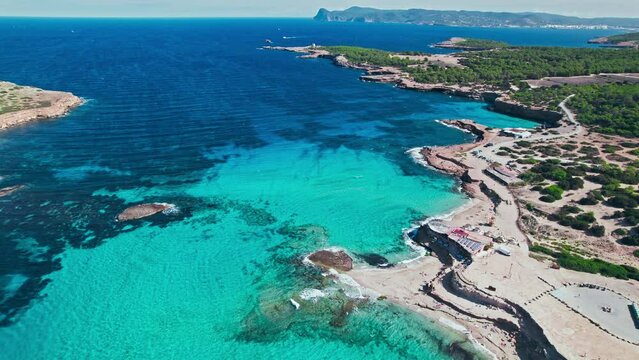 Bluish-turquoise mediterranean sea with corals by the seashore beach in Ibiza. Cala Comte and Escondida, Paradise-alike location with green forest and crystal water on the Balearic Islands, Spain