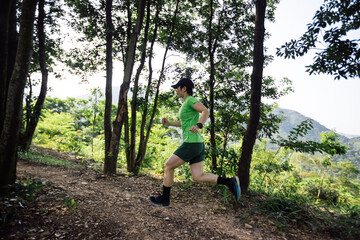 Woman trail runner running at tropical forest mountain peak