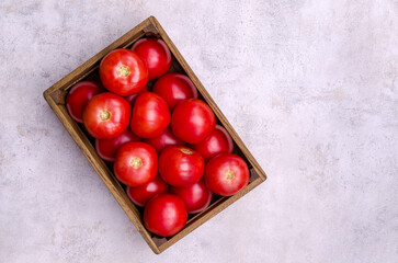 Large raw red tomatoes in a wooden box