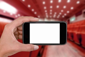 Human holding a smartphone and buying movie tickets online, cinema hall and seats in the background