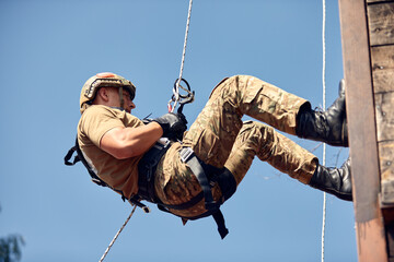 Military soldier climbing net during obstacle course in boot camp