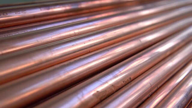 Metal, copper pipes stack with shiny reflections at warehouse. Plumbing, round tube sewerage products, manufacturing for building and construction, business production. Close up pan.