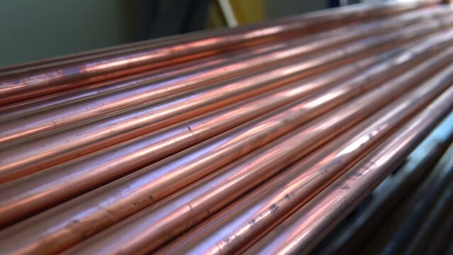 Metal, copper pipes stack with shiny reflections at warehouse. Plumbing, round tube sewerage products, manufacturing for building and construction, business production.