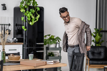 Man taking off his jacket standing in apartment