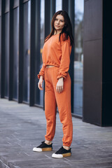 Fototapeta premium Young sporty woman in an orange sport suit
