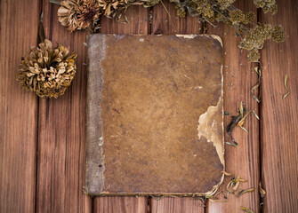 Blank shabby old book with dried wild flowers on wooden table