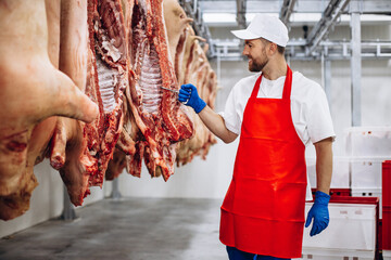 Man butcher standing in meat freezer holding hook