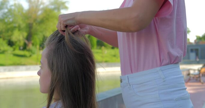 Mother making hairstyle french braid her daughter