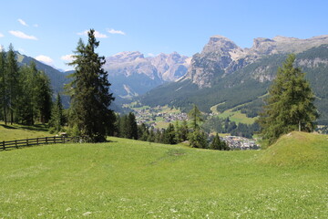 Coravara, Italy-July 16, 2022: The italian Dolomites behind the small village of Corvara in summer days with beaitiful blue sky in the background. Green nature in the middle of the rocks.