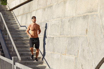 Young athlete man do morning run. Male runs up the stairs doing cardio exercises.