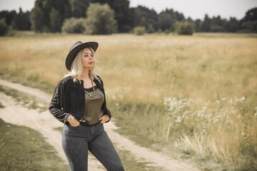 Woman in American country style,  suede leather boho jacket and cowboy hat at nature