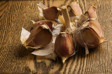 Garlic head with slices on a wooden countertop.