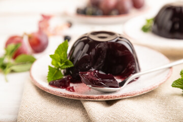 Black currant and grapes jelly on white wooden. side view, selective focus.