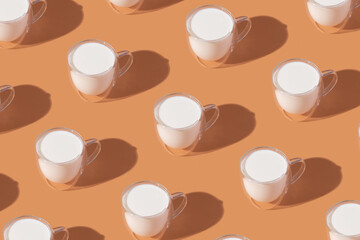 Milk in a glass pattern on orange colored background, dairy diet concept