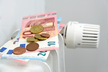 Euro banknotes and coins on a heating radiator, concept for rising energy prices and inflation,...