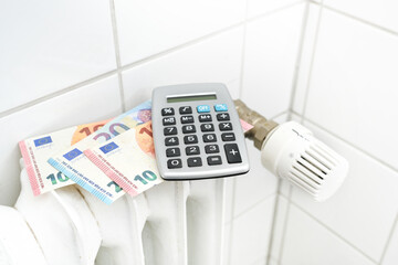 European notes and a calculator on an old heater, concept for saving energy costs during inflation,...