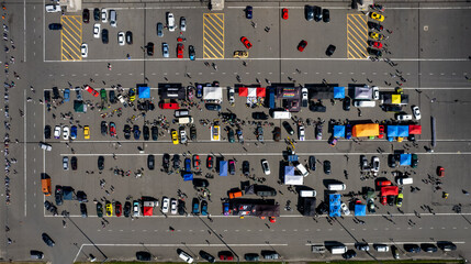 Colorful cars and people in a large parking lot as seen from above (aerial drone photo). Near...