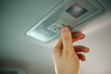 Man turning off interior lighting in car.