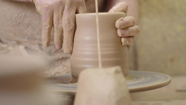 A potter crafting a ceramic pot with his hands on a potter's wheel
