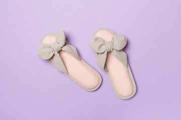 Soft pink slippers on color background, top view