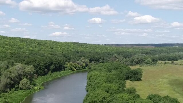 flying over the river among hills and clouds in spring, panoramic view.