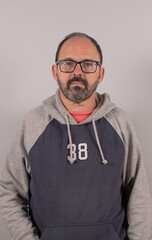 Close-up man in his 60s wearing eyeglasses, against gray wall background with copy space
