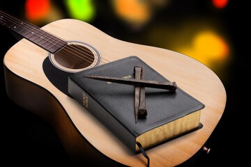 Holy Bible with acoustic guitar and religious crucifix cross on desk, gospel music concept