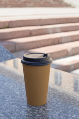 Take Away Coffee Cup. Coffee paper cup with black lid left on the street