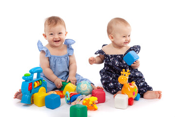 Two cute baby girls playing with toys, isolated on white. Having fun, smiling