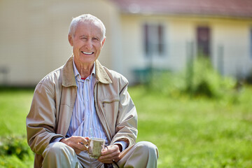 Toothy smile elderly man 75 years old sits outdoors in front of his house.