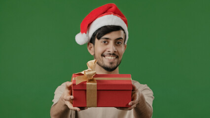 Arabian man in red Santa hat holds gift large red box with gold ribbon wishes new year Christmas celebration friendly indian guy showing present smiling arab afford pleasant surprise birthday concept