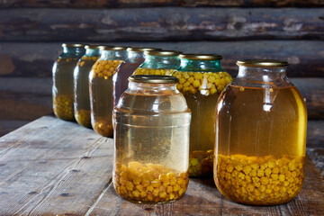 Cloudberry home canning, jars of berry compote are on table in barn.