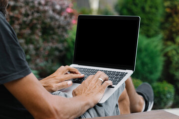 a man works in nature, sitting in a chair with a laptop