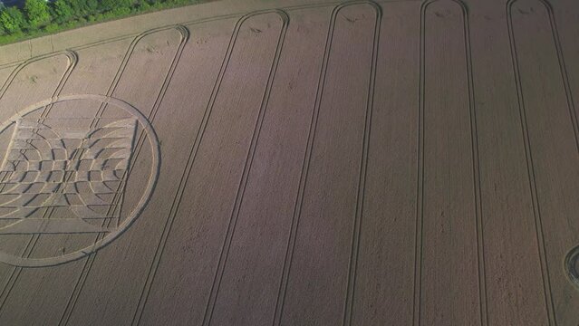 Drones captured aerial footage of crop circles in a field of yellow grain in the UK's Micheldever Station with nearby traffic.