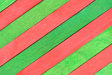 Colored green and red wooden planks. Wall made of wooden planks. Alternating red and green boards are arranged diagonally. Bright Christmas wooden textured background in two colors. Table top view.