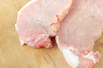 Raw sirloin steak on chopping board with salt and pepper on wood background.