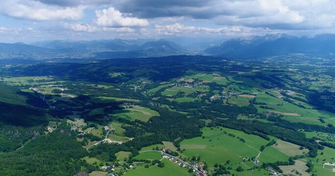Aerial shot of green countryside with fields, forest and moutains