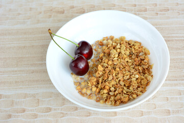 muesli with milk in white bowl decorated with cherries, close-up