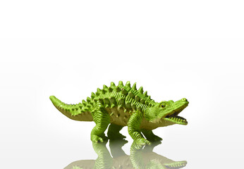 Figurine of a green dinosaur with spikes isolated on a white background with reflection added