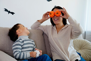 Young beautiful woman with her three year old son preparing decorations for halloween at home. Mom...